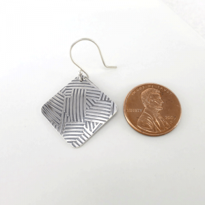 Sculpted chic oxidized sterling silver earrings featuring a rounded square shape decorated with geometric lines.