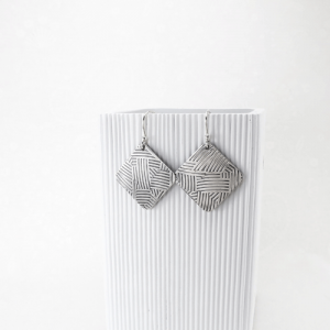 Sculpted chic oxidized sterling silver earrings featuring a rounded square shape decorated with geometric lines.