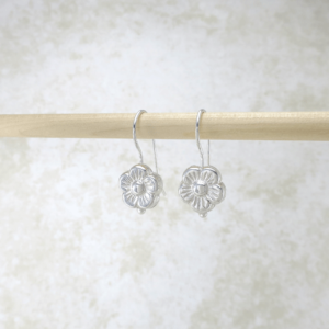 Silver dangle earrings featuring puffy daisy charms suspended from hooks, adding a touch of whimsy and elegance to any ensemble.